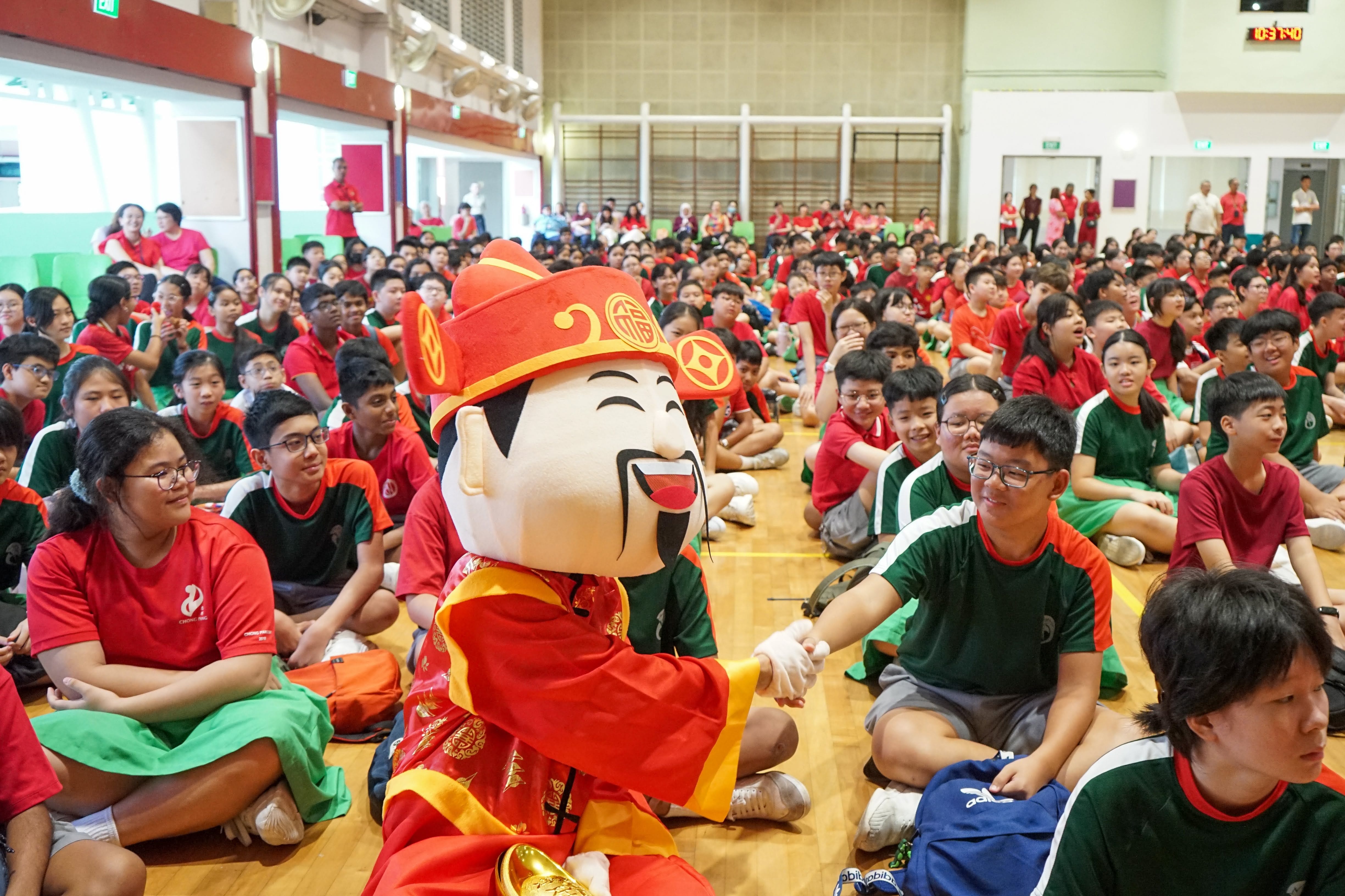 Photo of our students in the school hall sitting down with the "Cai Shen" also known as God of Wealth during chinese new year celebration in school.